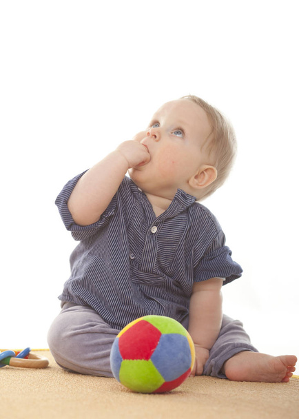 baby boy looking upwards sitting on carpet, isolated white - Foto, Bild