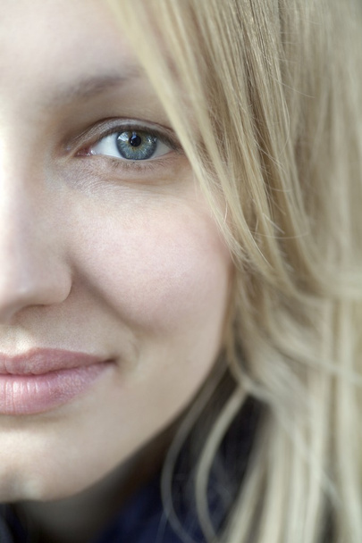 Half face of smiling blonde woman with blue eyes - Foto, imagen