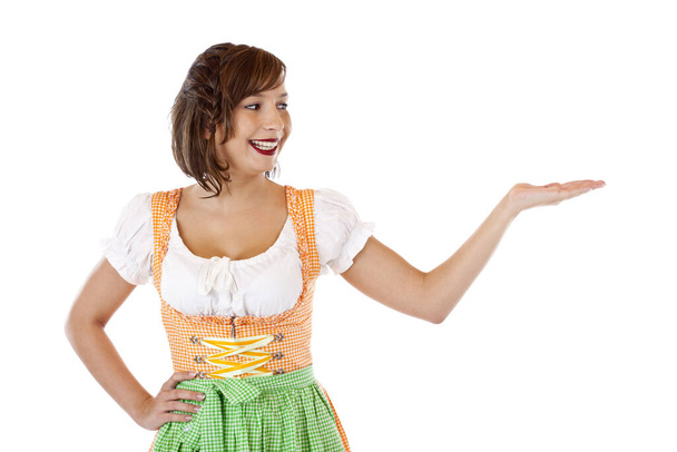 Pretty woman in Dirndl looks at advertising in her hand with a laugh - Фото, изображение