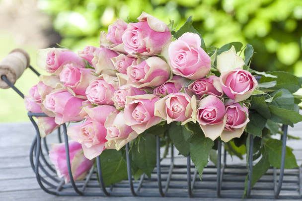 beautiful roses in a basket on a wooden table - Foto, Imagen