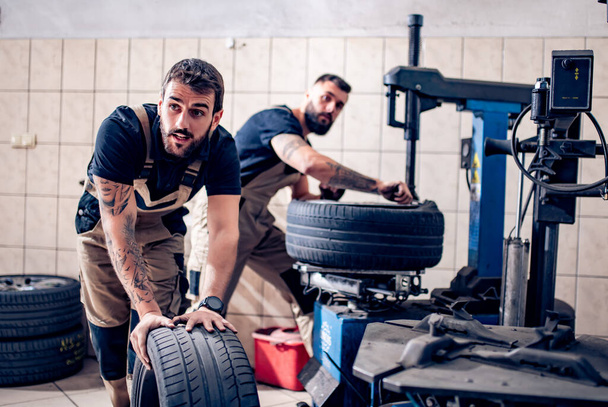 Meccanico che lavora su pneumatici per auto nel suo negozio
 - Foto, immagini