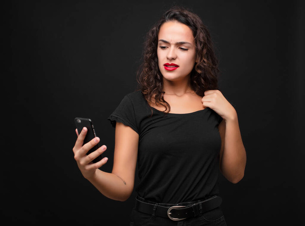 young pretty woman feeling stressed, anxious, tired and frustrated, pulling shirt neck, looking frustrated with problem holding a smartphone - Foto, immagini
