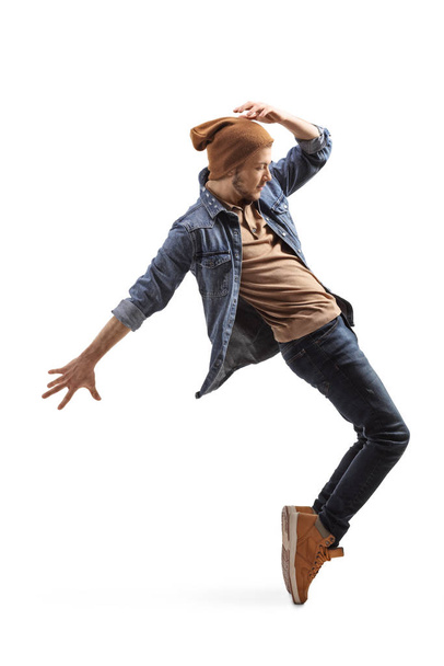 Young guy in jeans and woolen hat dancing on tiptoes - Foto, Imagen