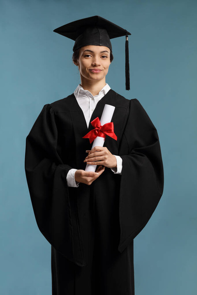 Female student in a graduation gown holding a diploma  - Φωτογραφία, εικόνα