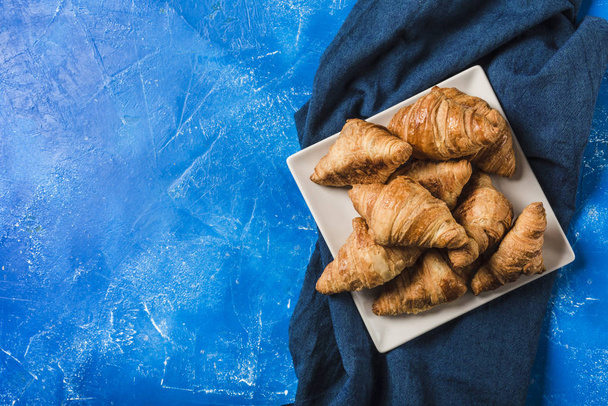 Freshly baked French croissants on a square plate with a dark bl - Valokuva, kuva