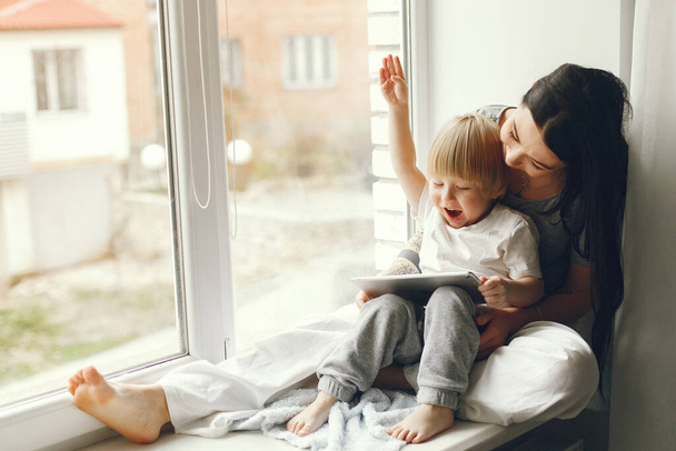 Mother and little son sitting on a windowsill - Photo, image
