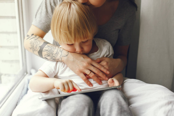 Mother and little son sitting on a windowsill - Foto, imagen