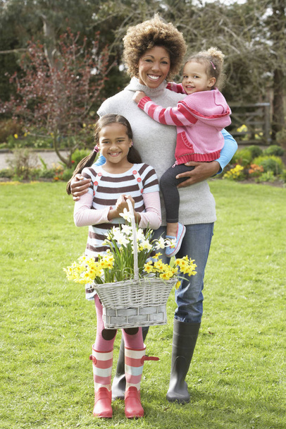 Mother And Children Holding Basket Of Daffodils In Garden - Foto, Imagen
