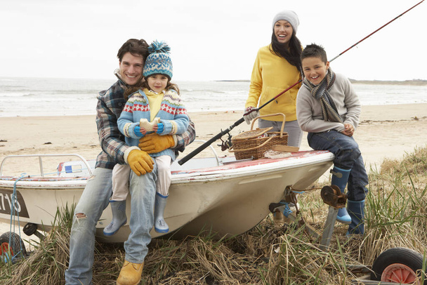 Family Group Sitting On Boat With Fishing Rod On Winter Beach - Φωτογραφία, εικόνα