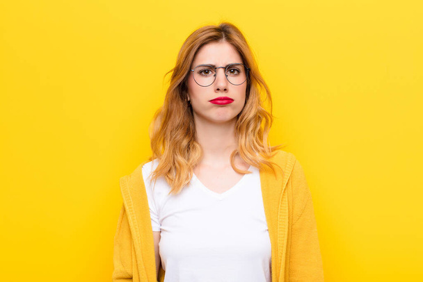 young pretty blonde woman feeling sad and whiney with an unhappy look, crying with a negative and frustrated attitude against yellow wall - 写真・画像