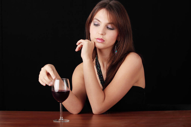 Young woman with glass of red wine, isolated on black background - Foto, Imagen