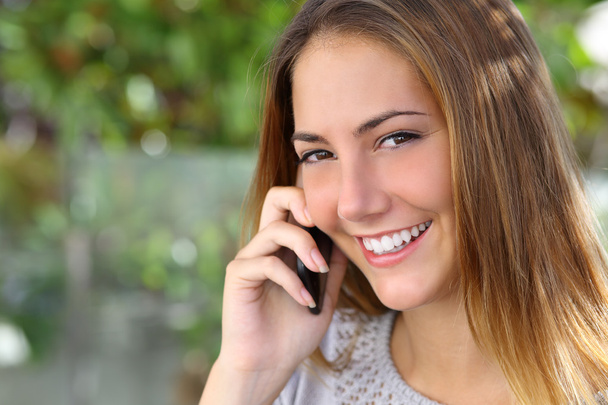 Beautiful woman with a perfect white smile talking on the mobile phone - Zdjęcie, obraz
