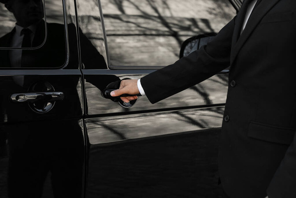 Driver opening door of luxury car, closeup. Chauffeur service - 写真・画像