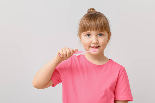 Malá dívka se zubním kartáčkem na světlém pozadí - Fotografie, Obrázek