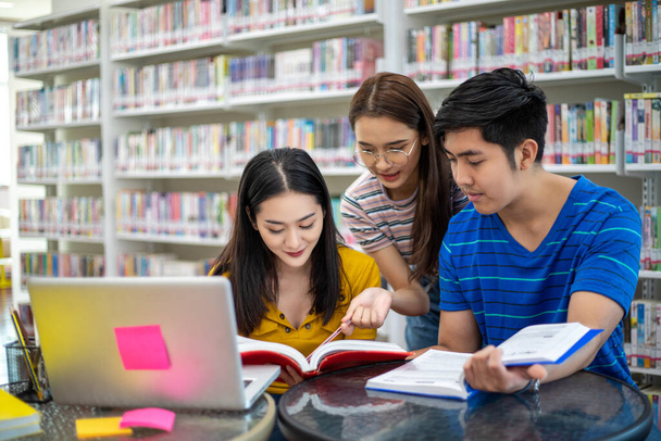 Groupe Asiatique Étudiants Sourire et lire livre et à l'aide d'un ordinateur portable
  - Photo, image