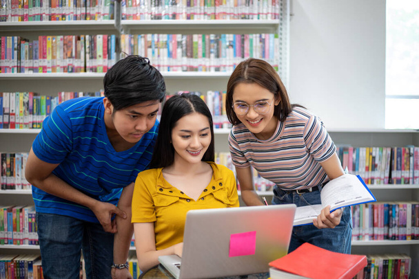 Groupe Asiatique Étudiants Sourire et lire livre et à l'aide d'un ordinateur portable
  - Photo, image