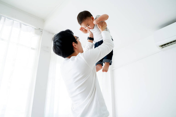 Asian father lifting his little own son up flying in the air - Valokuva, kuva
