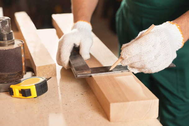 Professional carpenter working with wooden board at workbench, closeup - Fotó, kép