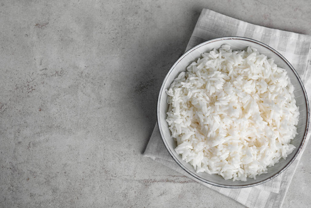 Bowl with tasty cooked rice on light grey table, flat lay. Space for text - Photo, Image