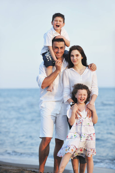 happy young family have fun on beach run and jump  at sunset - Foto, Bild
