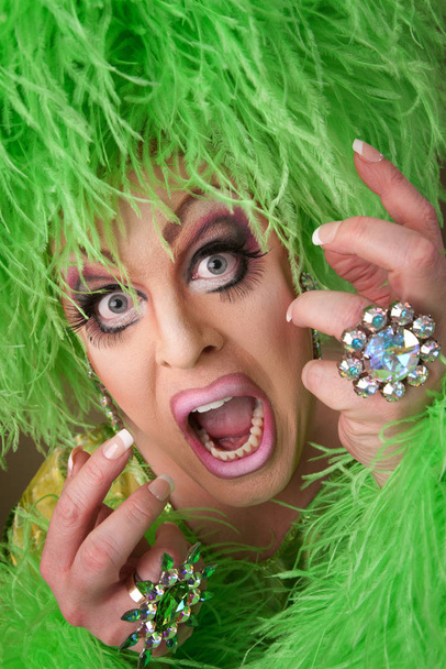 Large drag queen in green dress and wig dances on rug - Fotografie, Obrázek