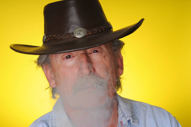 Old senior cowboy smoking a hand rolled cigarette - Fotoğraf, Görsel
