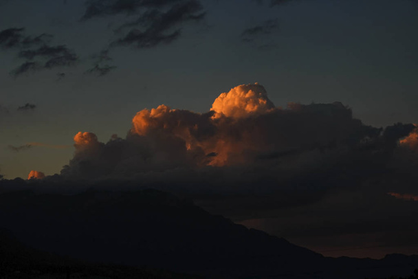 cielo scuro con nuvole di tempesta arancione sopra la catena montuosa
 - Foto, immagini