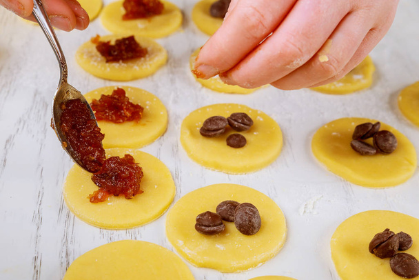 Woman filling raw cookie dough circles with jam. - Foto, Imagem
