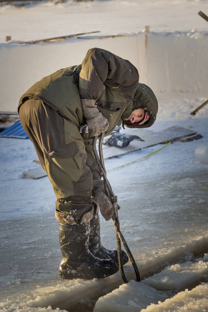 Фиттер со стальными щипцами вытаскивает ледяной блок
 - Фото, изображение