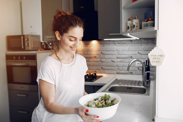 Elegant girl in a kitchen with salad - Φωτογραφία, εικόνα