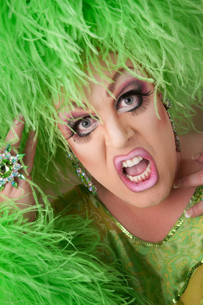 Scared drag queen wearing heavy makeup and boa hat  - 写真・画像