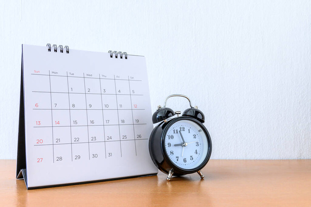 Calendario con días y reloj en mesa de madera
 - Foto, imagen