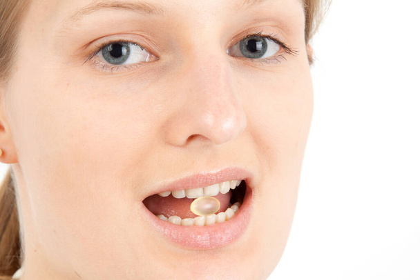 young woman with a pill between her teeth - Φωτογραφία, εικόνα