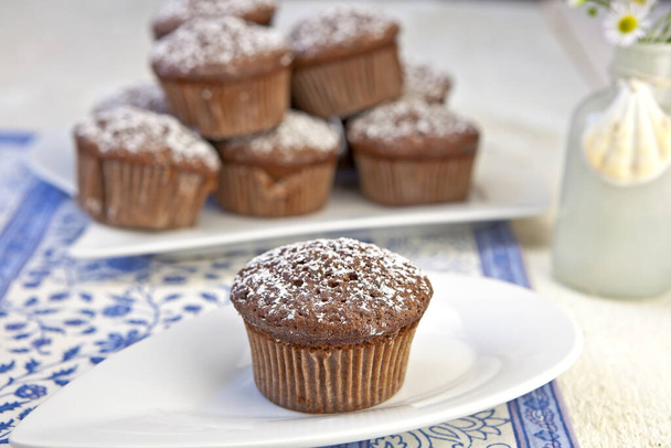 freshly baked chocolate muffins sprinkled with powdered sugar - 写真・画像