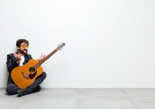 young man with guitar on floor in room - Foto, Bild