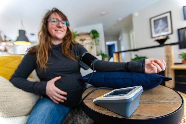 Pregnant woman uses blood pressure meter - Photo, Image