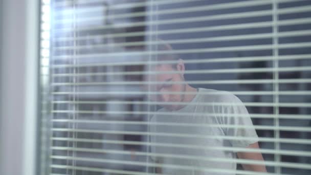 Vista a través de la ventana, el hombre se puso ropa de trabajo protectora blanca
  - Metraje, vídeo