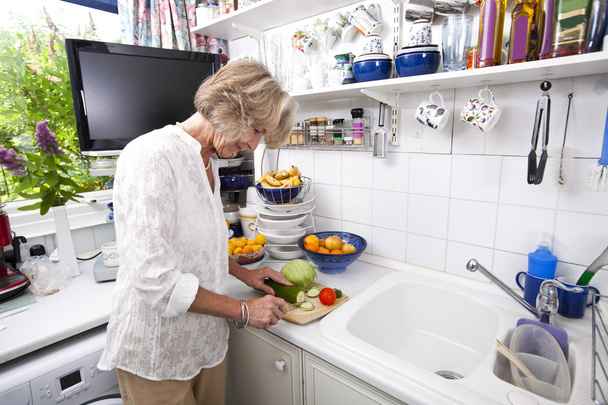 Senior woman chopping fresh vegetables - Photo, image