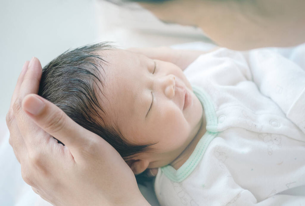 Közelkép egy baba alszik kényelmesen az anya karjaiban - Fotó, kép