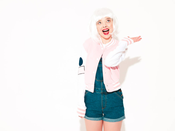 Young sexy smiling hipster girl in white wig and red lips.Beautiful trendy woman in summer clothes.Model isolated on white in studio.Positive female going crazy - Fotoğraf, Görsel