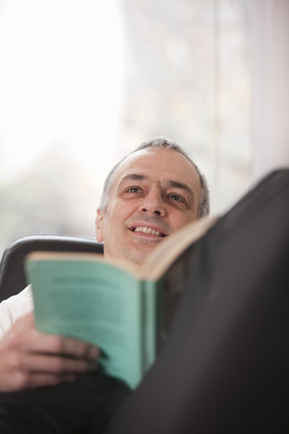 Mid adult man relaxing at home reading a book - Foto, Imagem