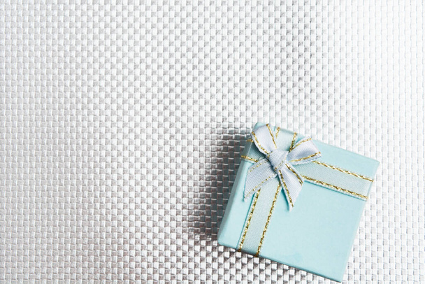 Caja de regalo azul con lazo plateado sobre fondo texturizado plateado
 - Foto, imagen