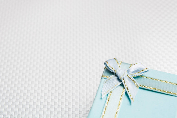 Blue gift box with silver bow over silver textured background - Foto, imagen