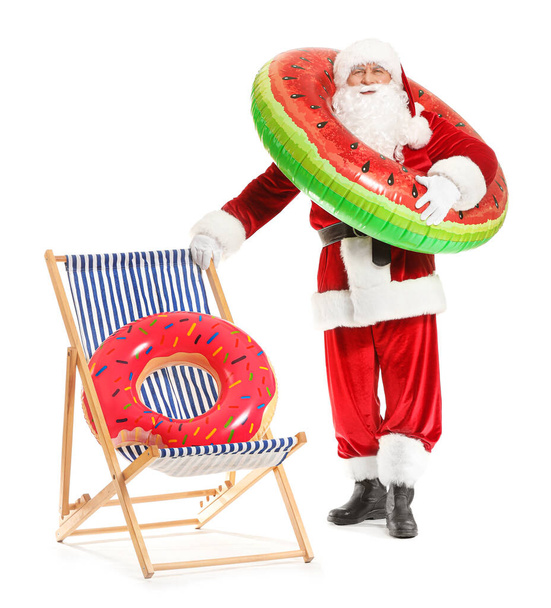 Santa Claus with swimming rings and sun lounger on white background. Concept of vacation - Photo, Image