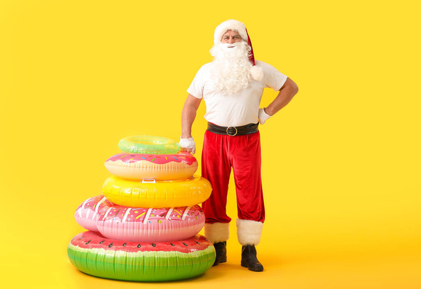 Санта-Клаус с плавательными кольцами на цветном фоне. Концепция отпуска
 - Фото, изображение