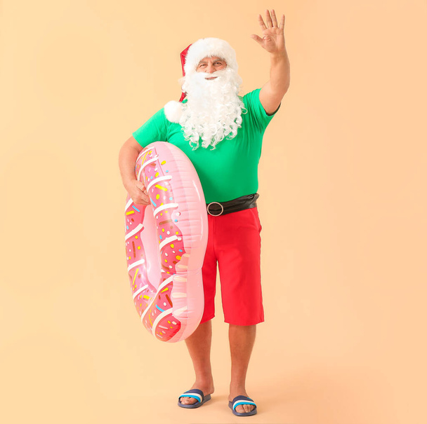 Санта-Клаус с плавающим кольцом на цветном фоне. Концепция отпуска
 - Фото, изображение