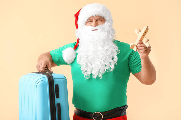 Santa Claus with luggage and toy airplane on color background. Concept of vacation - Fotoğraf, Görsel