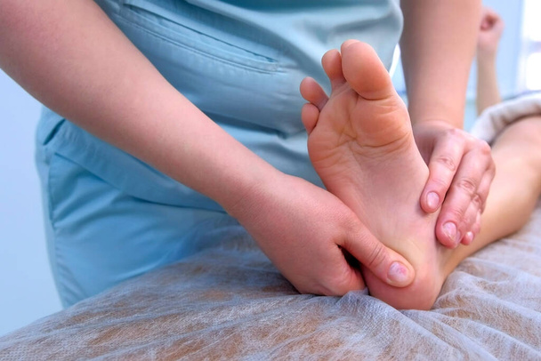 Doctor massagist making therapy massage to child boy on foot in clinic, closeup. - Φωτογραφία, εικόνα