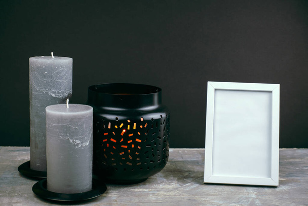 close up details of the interior of the room with a black wall, gray candles and a white empty photo frame - Foto, imagen