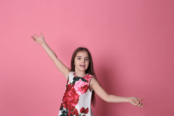 smiling girl of eight years old in a beautiful dress on a pink background joyful spring mood - Foto, immagini